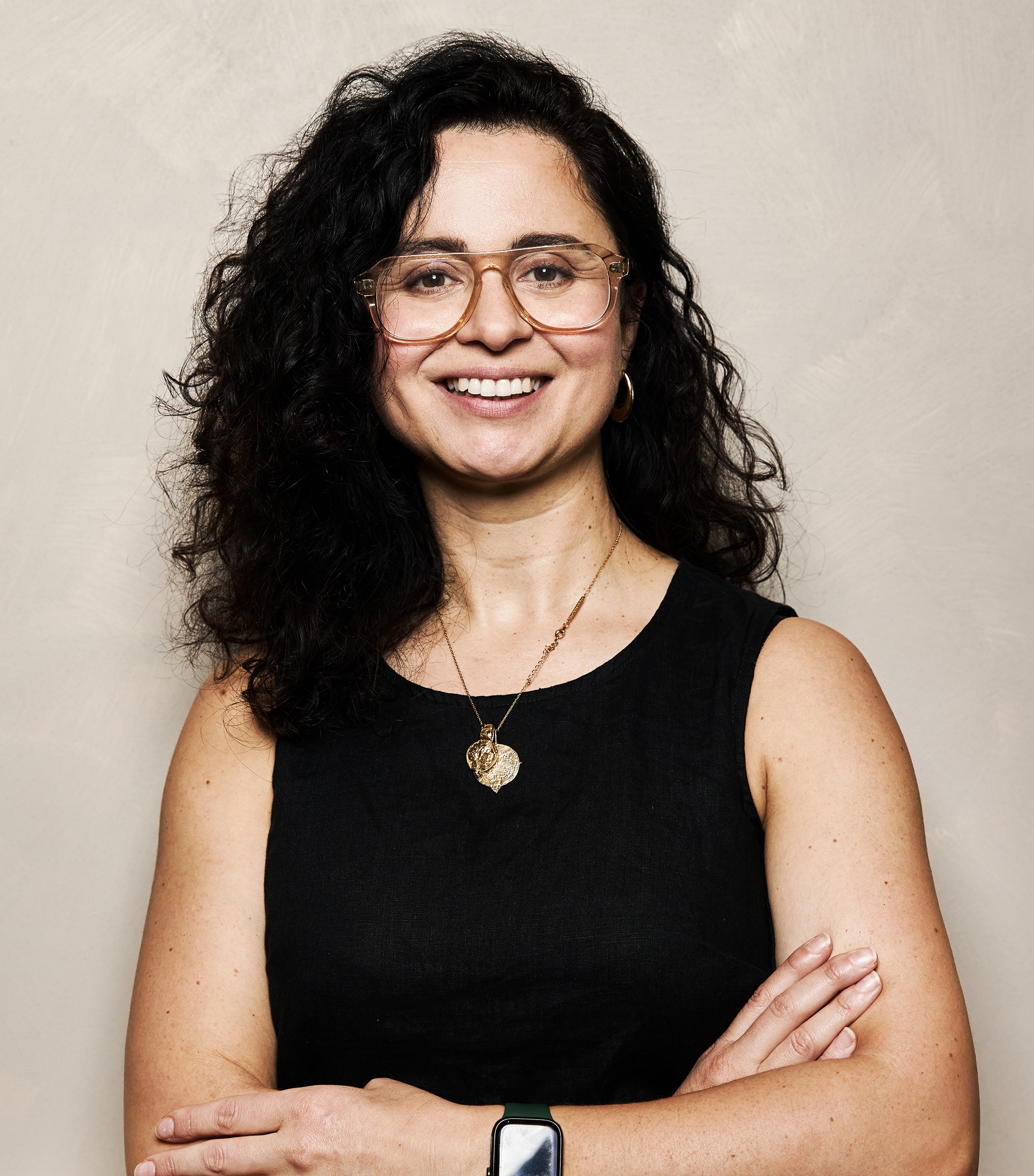 Portrait of a man with brown hair and glasses on a flat gray background.